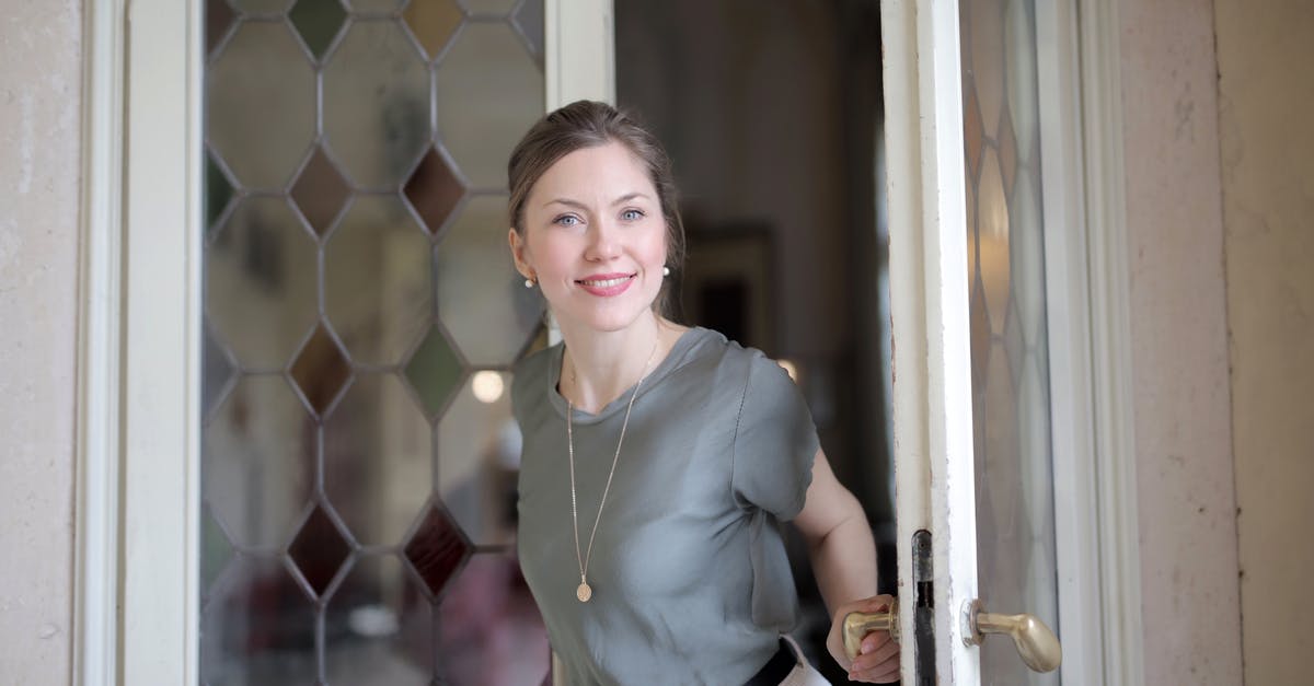 What is the dress code for the Vienna State Opera (Standing Room Section)? - Young smiling female in casual outfit looking at camera and holding on doorknob while entering through stained glass vintage door in ancient building