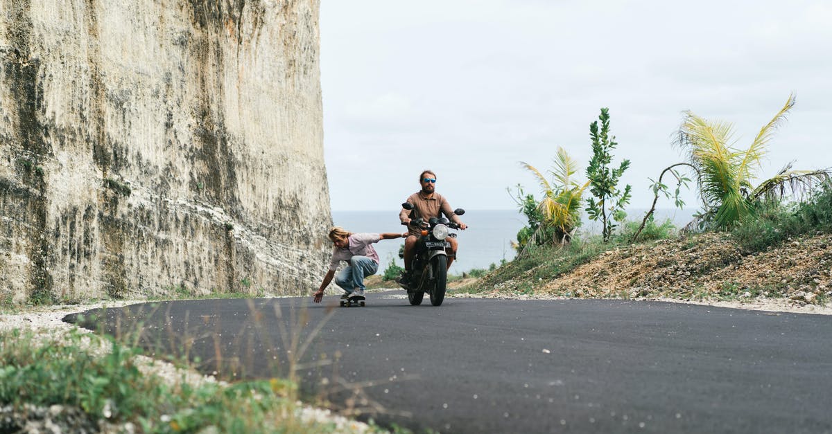 What is the experience of driving in Thailand? [closed] - Man on motorbike riding man on skateboard in sitting position