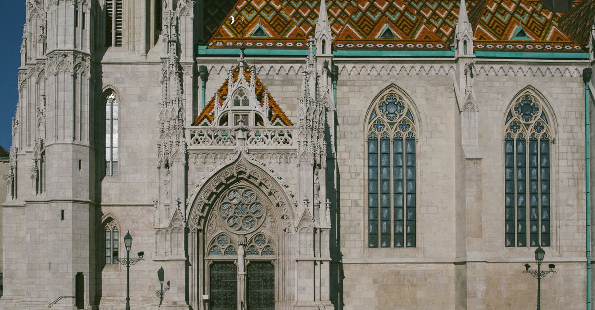 What is the location of this 19th century photo of the Andes? - Exterior of Matthias Church with ornamental windows and colorful roof on street in sunny day