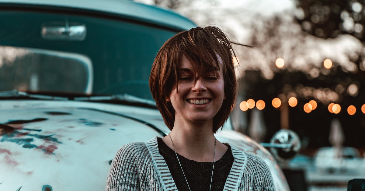 What is the most beautiful and pleasant city for a citytrip? Vienna or Budapest? [closed] - Optimistic smiling female in casual comfy outfit standing with eyes closed against old fashioned truck in evening