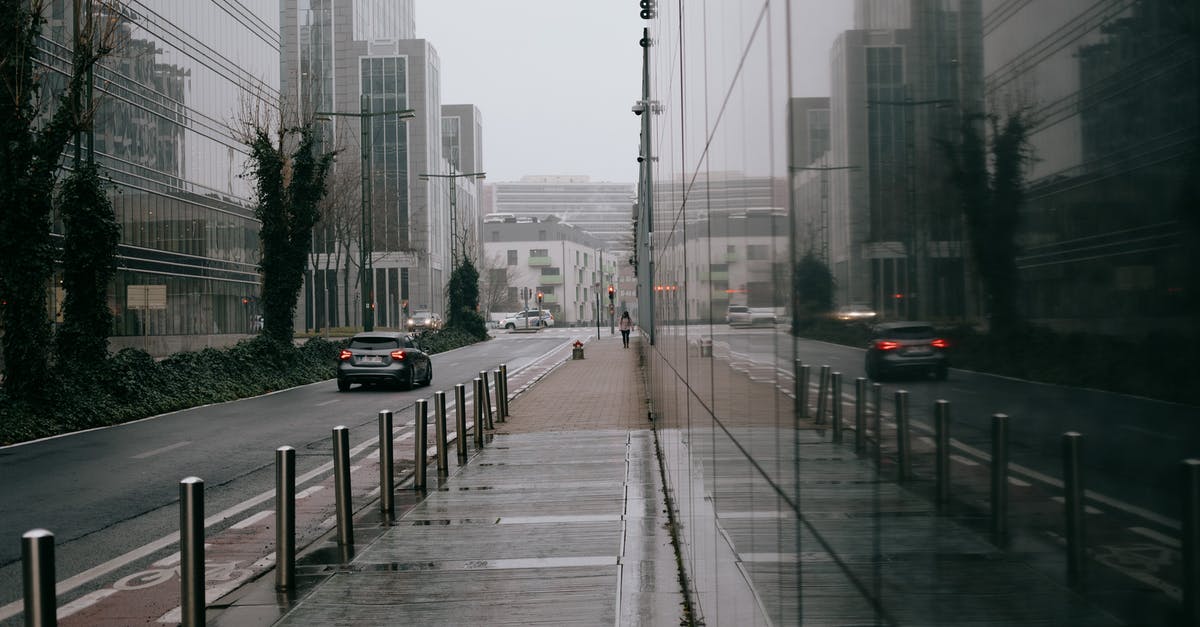 What is the most campsite-dense route between Belgium and the Tatras? - Modern city street with glass building on overcast rainy day