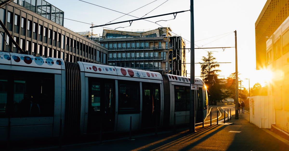 What is the most remote railway line in the world? - Tram riding on railroad on city street in summer in evening time near buildings