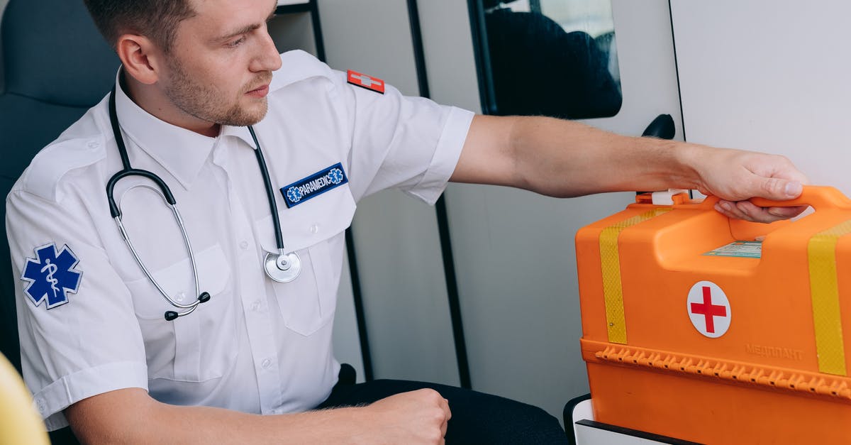 What is the non-emergency 24 medical assistance number in iceland? - A Man Sitting while Holding a First Aid Kit