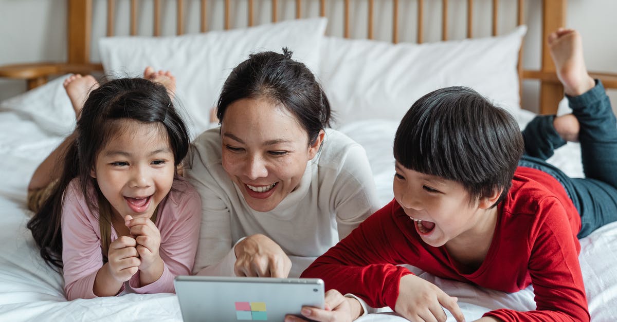 What is the point of checking in online? [duplicate] - Full body happy Asian mother pointing at screen tablet showing interesting information to cheerful kids while lying on cozy bed in light room