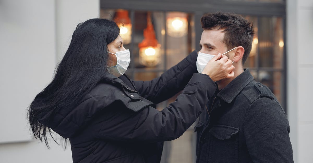 What is the typhoid fever risk for an un-vaccinated toddler in Mexico City? [closed] - Young careful couple adjusting medical masks against urban building