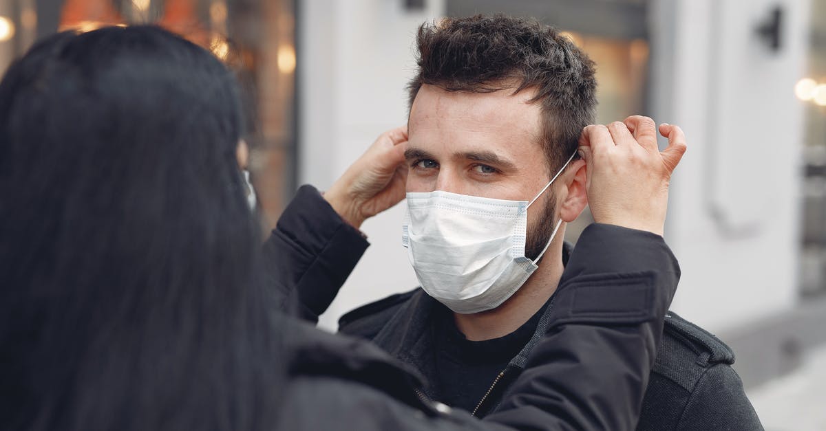 What is the typhoid fever risk for an un-vaccinated toddler in Mexico City? [closed] - Concerned woman in warm outerwear adjusting protective mask on face of bearded man on city street in cold season during coronavirus pandemic