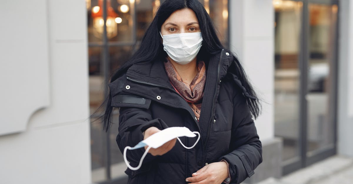 What is the typhoid fever risk for an un-vaccinated toddler in Mexico City? [closed] - Young woman wearing medical mask and black down jacket on urban street in cold season