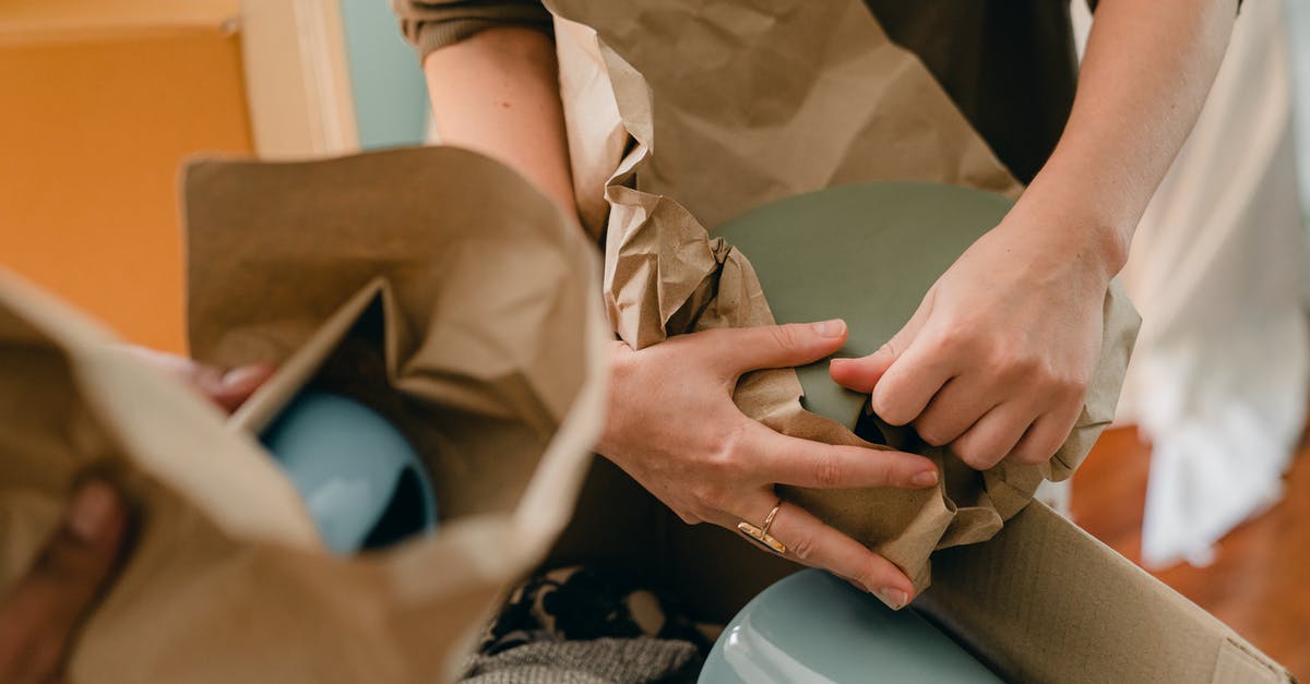 What is the youngest new natural landmass that can be visited? - Crop unrecognizable person packing ceramic tableware in parchment