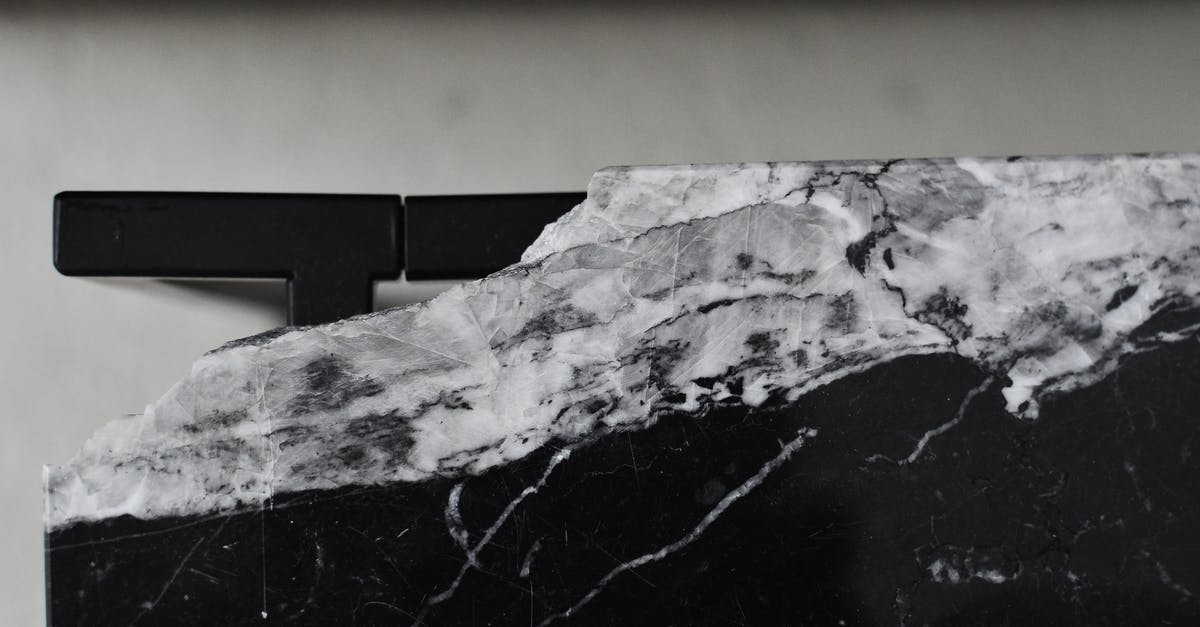 What is this black spot in Syria? - Top view of aged table with damaged marble surface on floor in house room in daylight