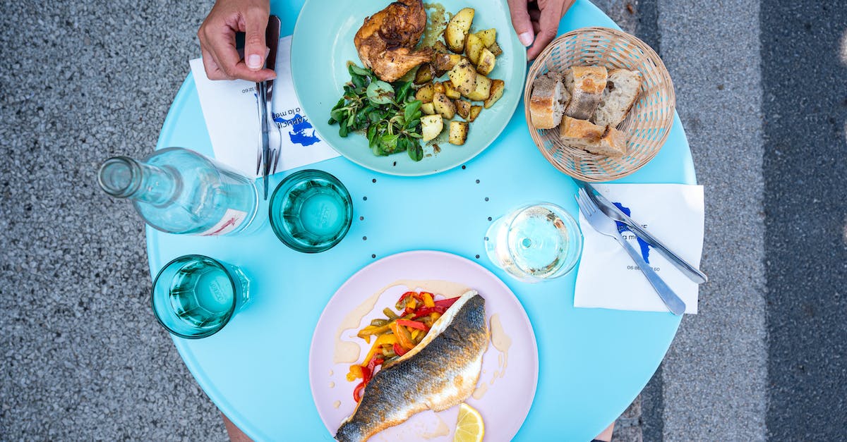 What is this Israeli street food dish? - Top view of crop anonymous people sitting at table with yummy food and glasses while having lunch in street cafe in daytime