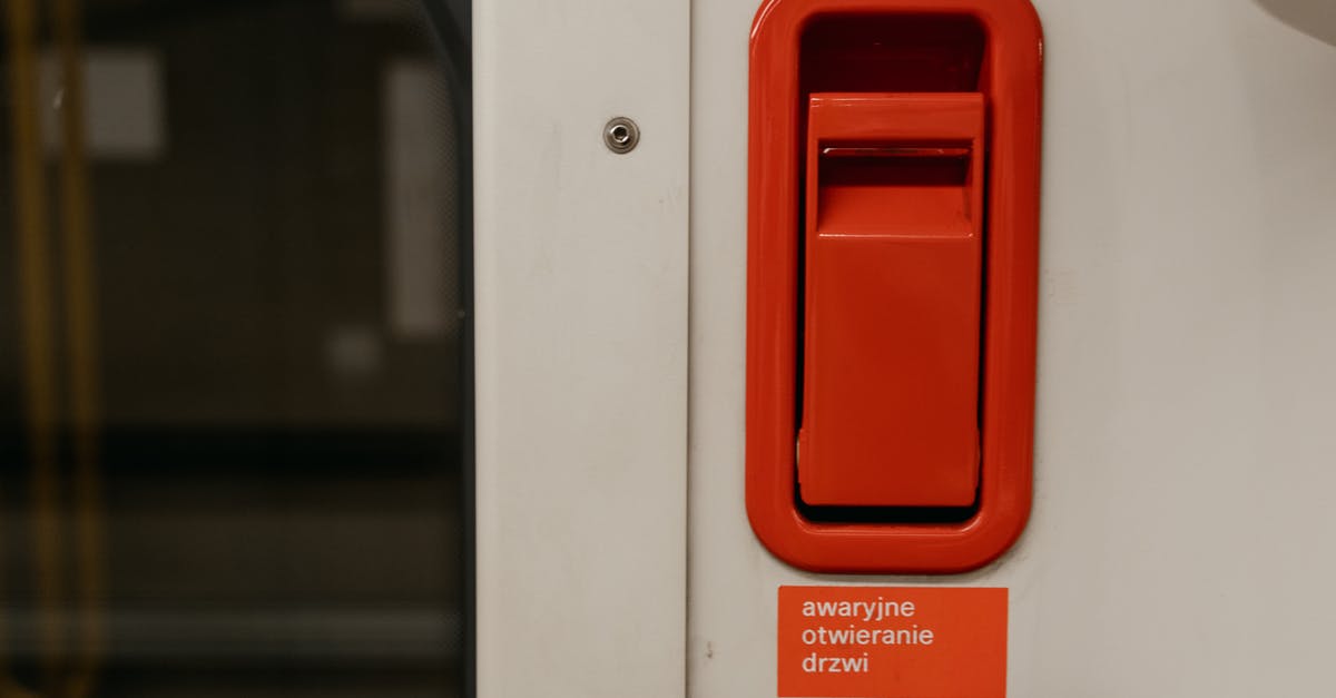 What is this lever in Argentinian toilets? - A White Door with Red Lever Above a Warning Sign