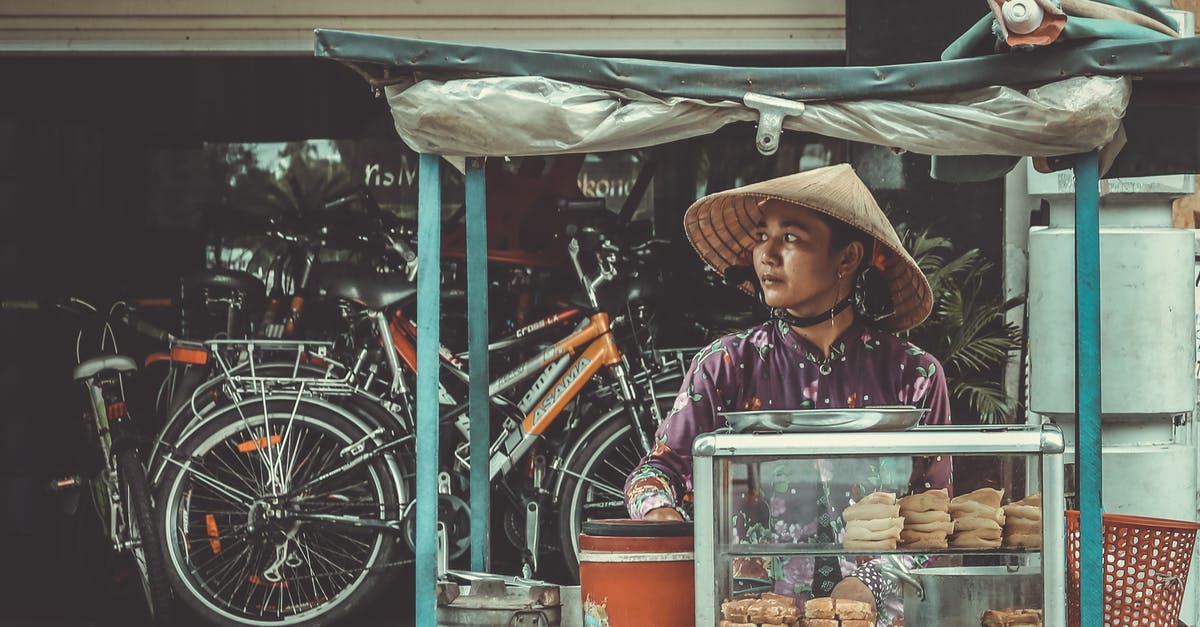 What kind of hat to wear for business in India? - Man Standing in Front of Food Stand