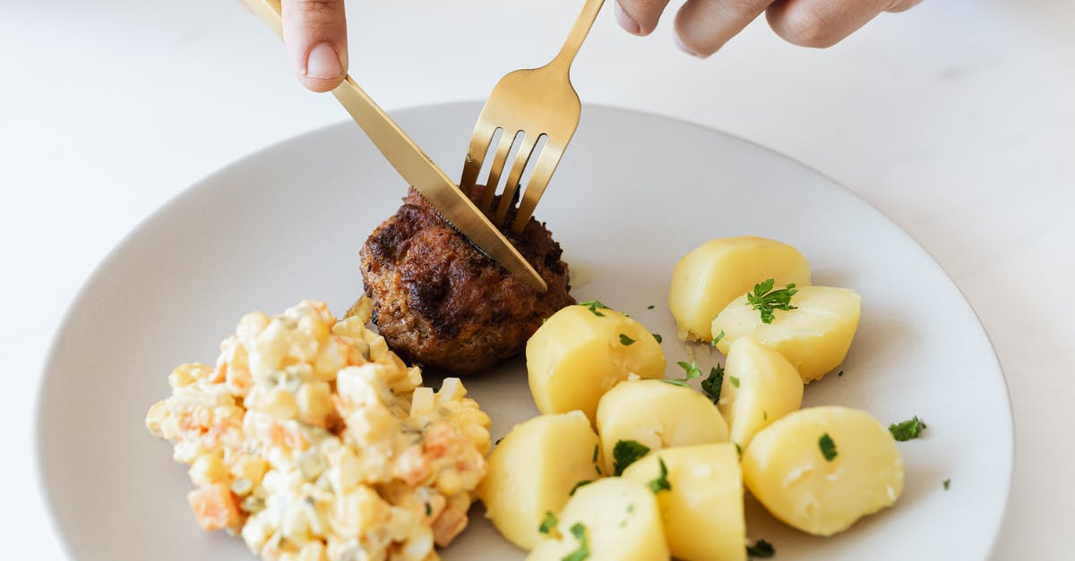 What meals are available on Russian trains? - From above of crop anonymous person cutting with cutleries fried juicy meat cutlet served on white plate with tasty boiled potatoes and Russian salad