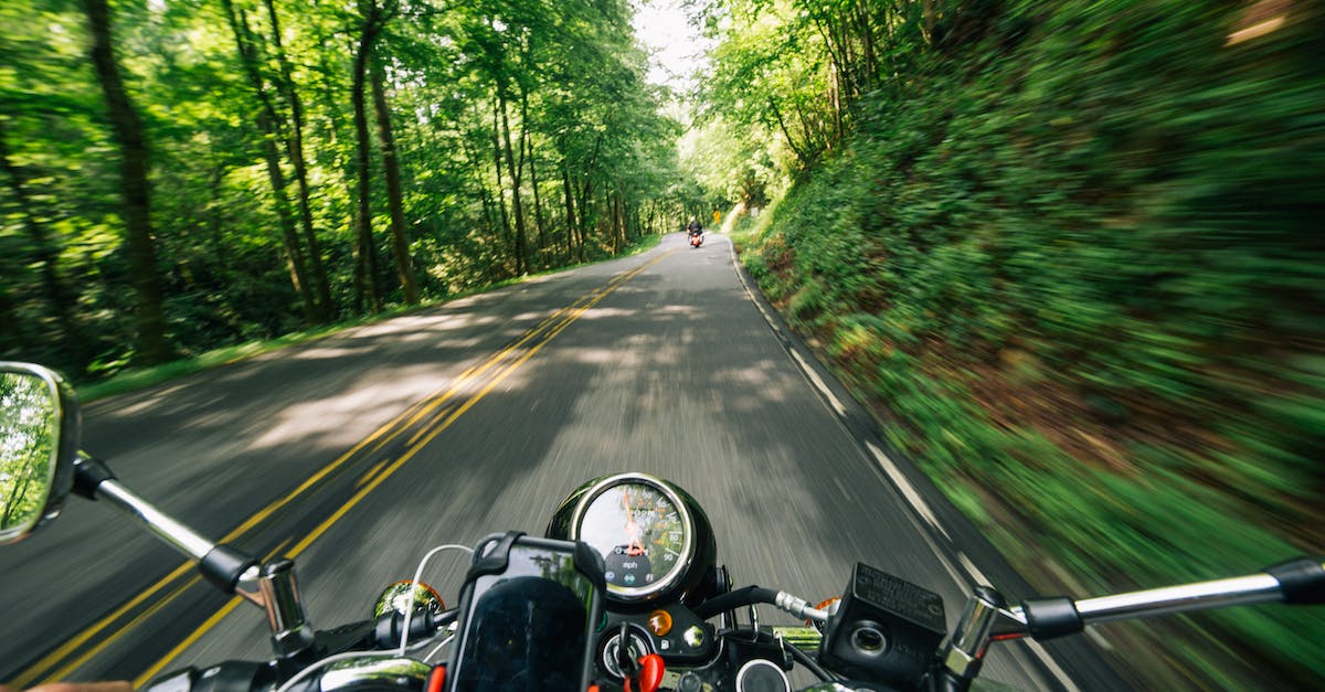 What measures can one take to keep a motorcycle safe during a road trip? - Photo of Person Riding Motorcycle on Road Between Trees