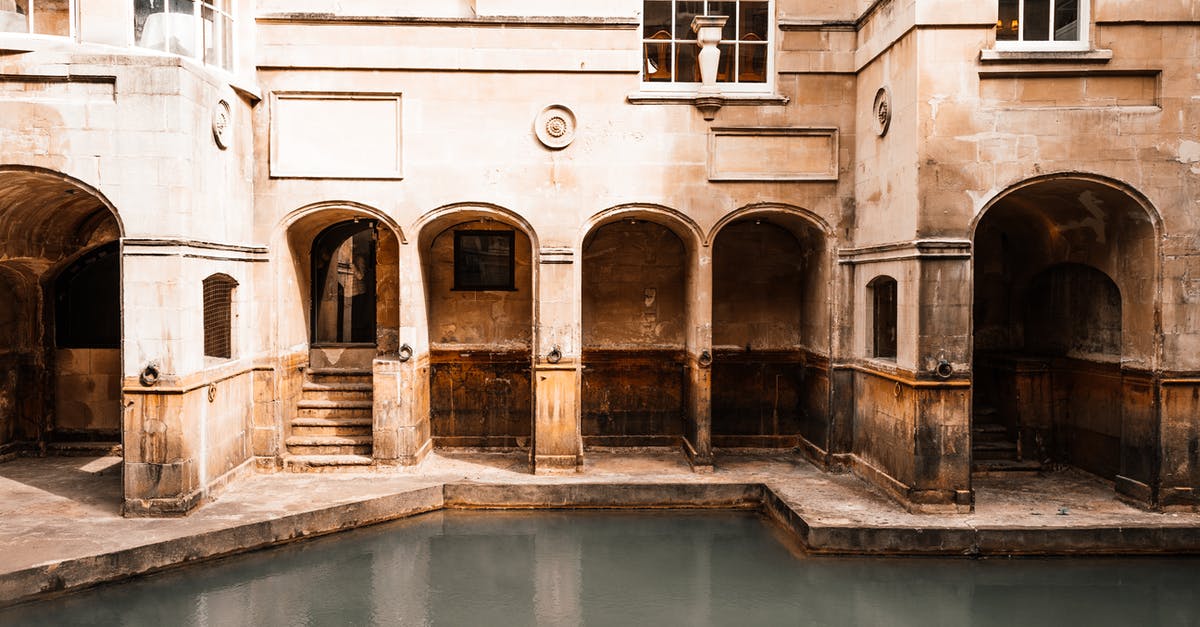 What places are considered outside Greater London? - Exterior of aged mansion with shabby walls and arched passages located near water canal in old city in sunny street