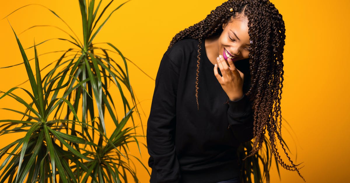 What should I do when my bags have been planted with bullets (or any malicious content)? - Cheerful young African American woman with Afro hairstyle touching lips while laughing against yellow background and looking down