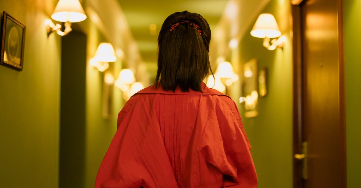 What should I expect when I stay in a hotel? - Woman in Red Dress Standing in the Hallway