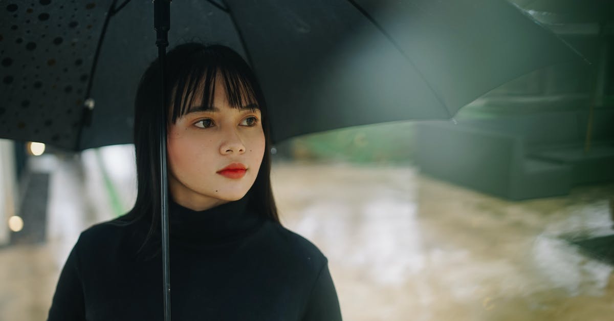 What should I wear in the tropics during the rainy season? - Photo of Woman Holding Black Umbrella