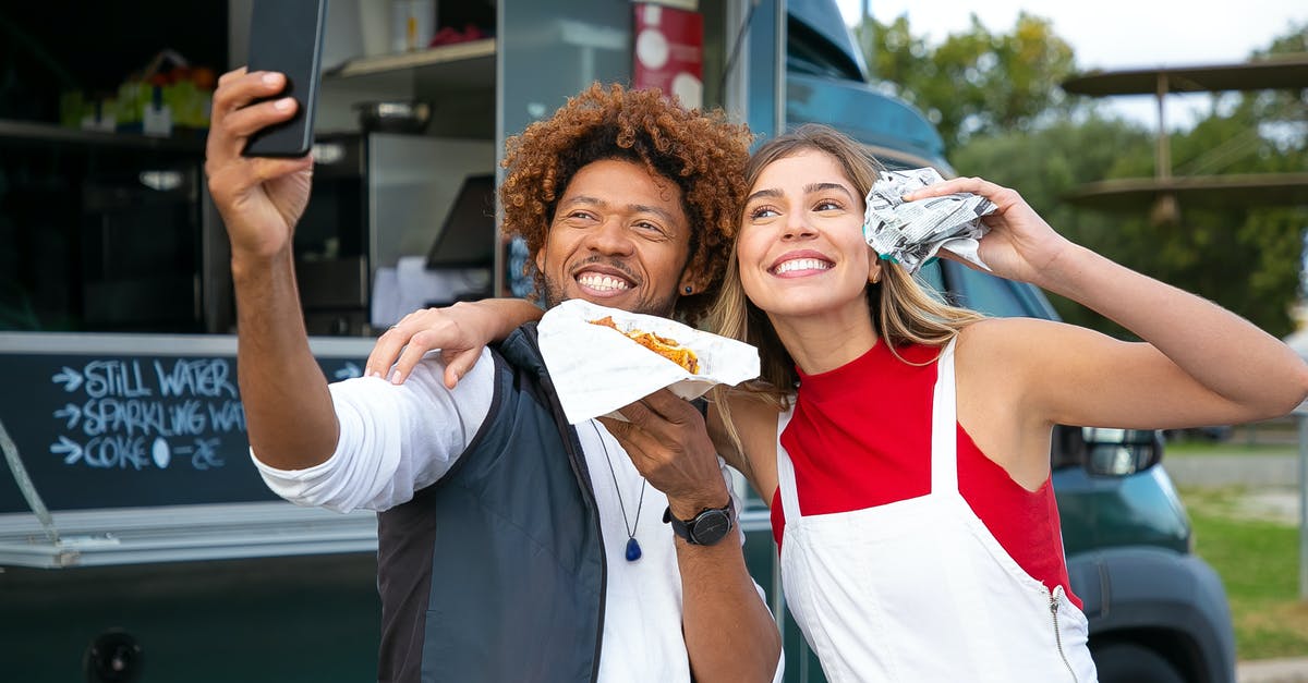 What street foods can I eat in Italy? - Happy multiethnic friends with burgers taking selfie near food truck