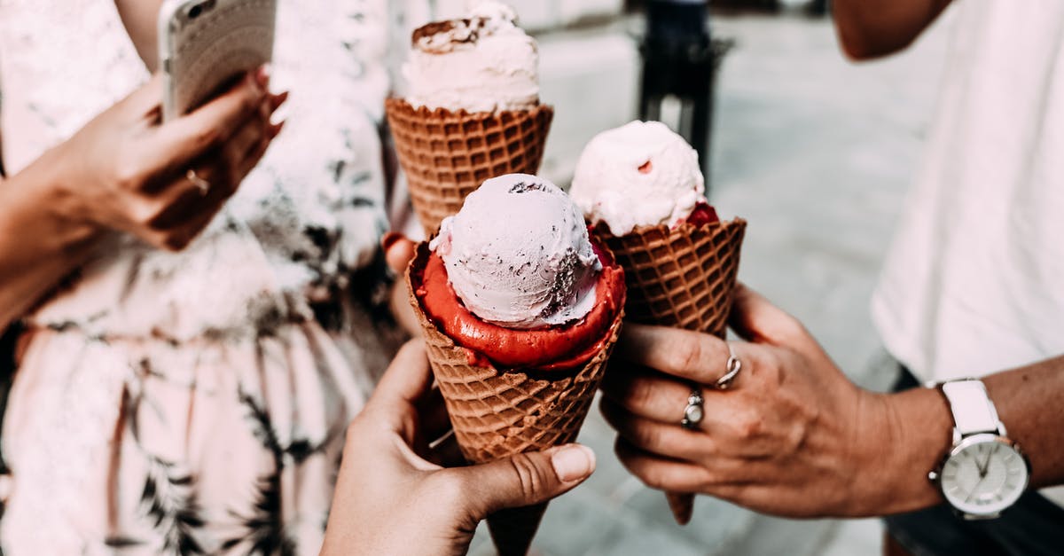 What street foods can I eat in Italy? - Crop anonymous friends in casual summer clothes clinking delicious cone ice creams while gathering on street