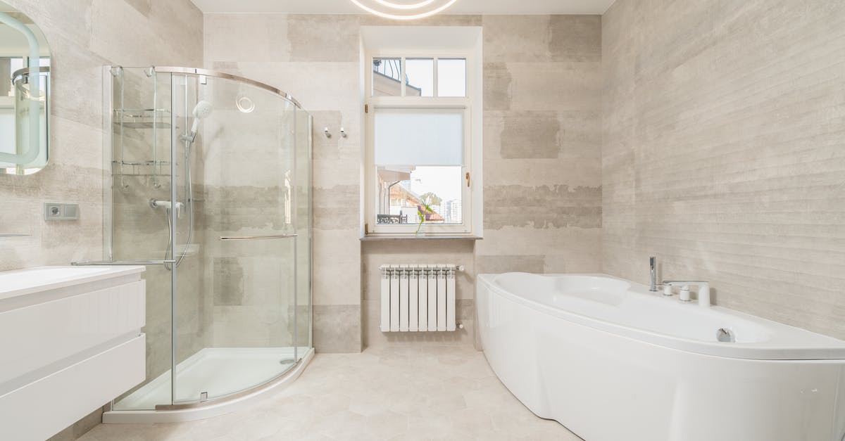 What style of bathroom facilities are in Hong Kong hotels? - Modern spacious light bathroom with white bath and glass shower cabin near window