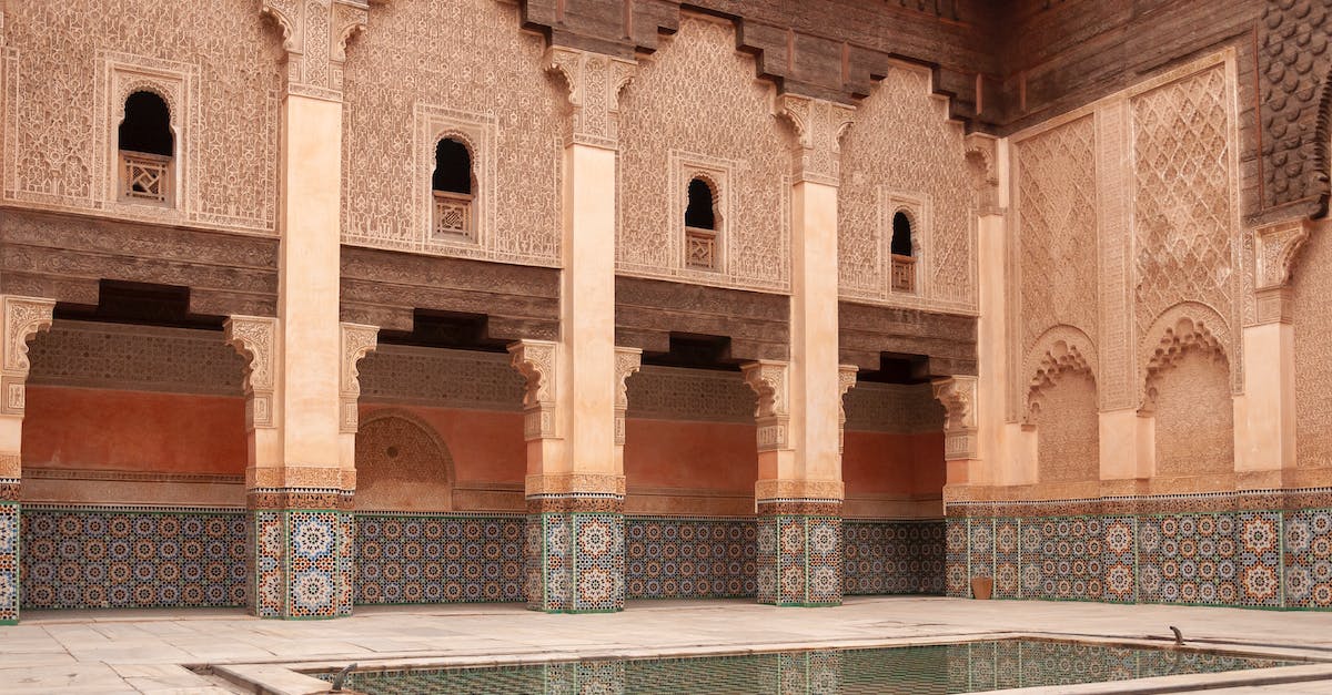 What supporting evidence is required for a Moroccan travel visa? - Main courtyard of ancient Ben Youssef Madrasa with arched passage and walls decorated with arabesque ornaments on sunny day in Marrakesh
