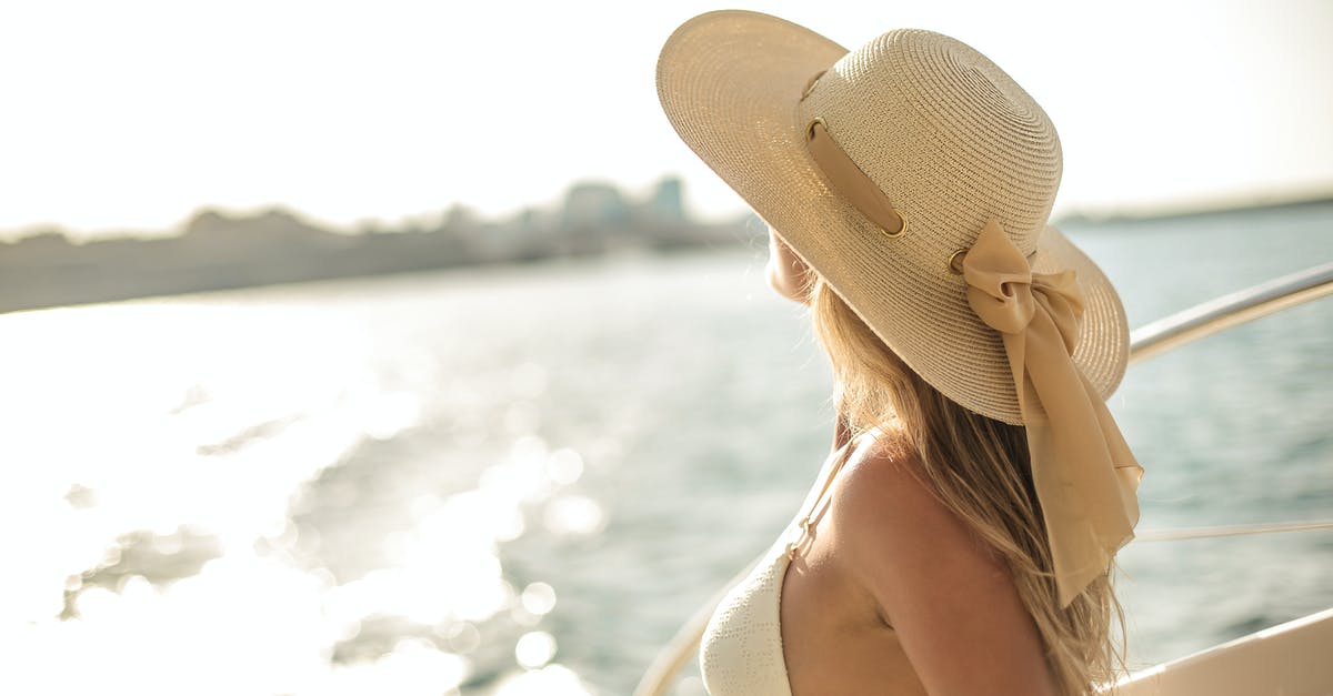 What time is used on board a cruise ship? - Back view of slim female in bikini top and straw hat enjoying trip on cruise boat on sunny day while relaxing during summer vacation and looking away