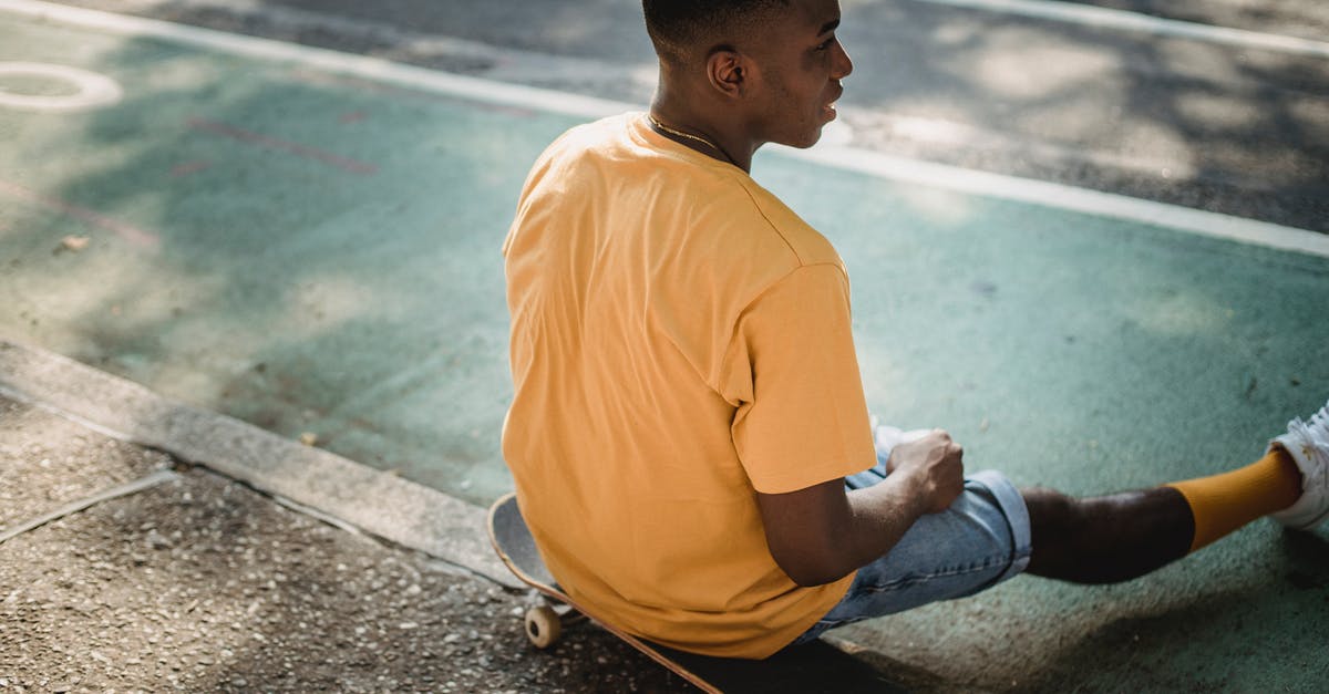 What time to reach Italian Train stations to board train(s)? - Trendy black guy sitting on skateboard after workout in sunlight