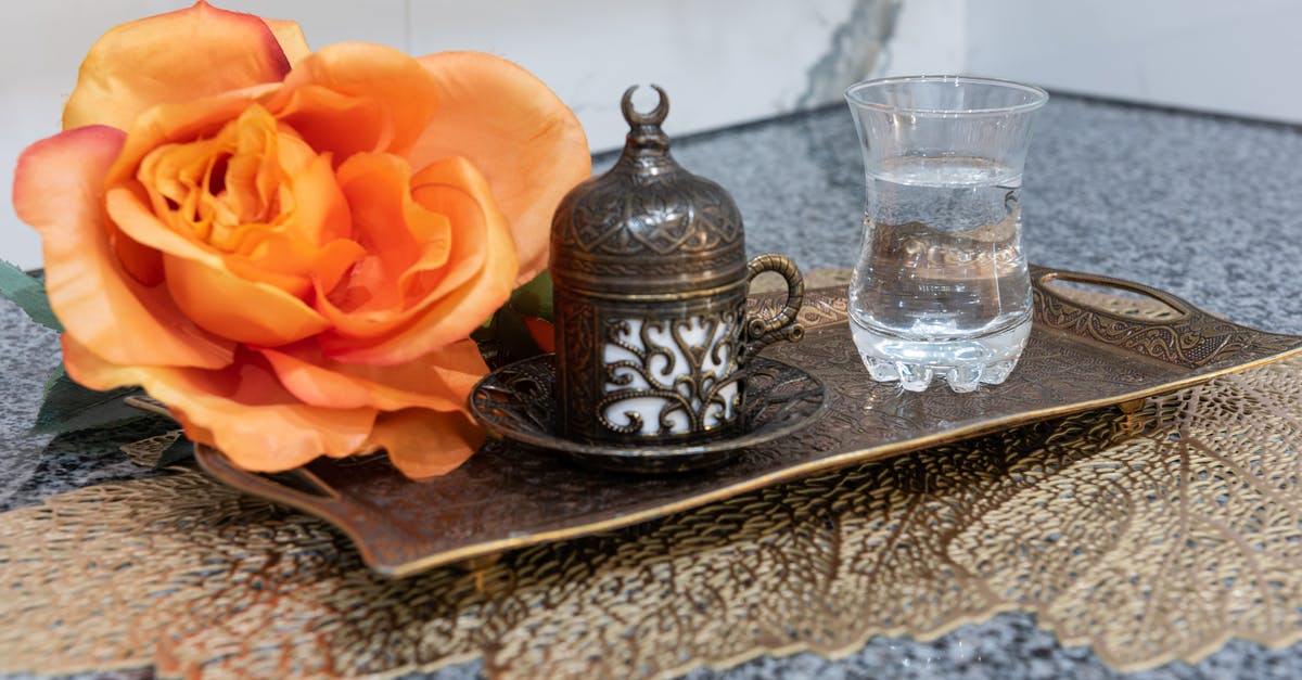 What to do with the water served with hot chocolate in Italy? - Metal authentic Turkish coffee mug with plate placed on tray with cup of water and big rose on table in room What to do with the water served with hot chocolate in Italy? - Metal authentic Turkish coffee mug with plate placed on tray with cup of water and big rose on table in room