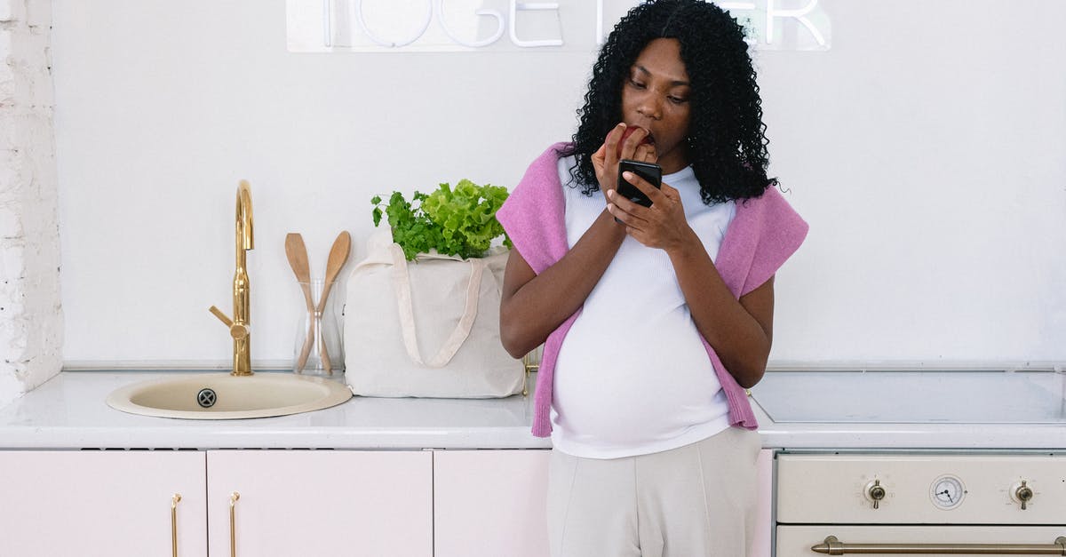 What to expect about the mobile phone usage during a flight to China and based on the CAAC regulations - Black pregnant woman with smartphone eating in kitchen
