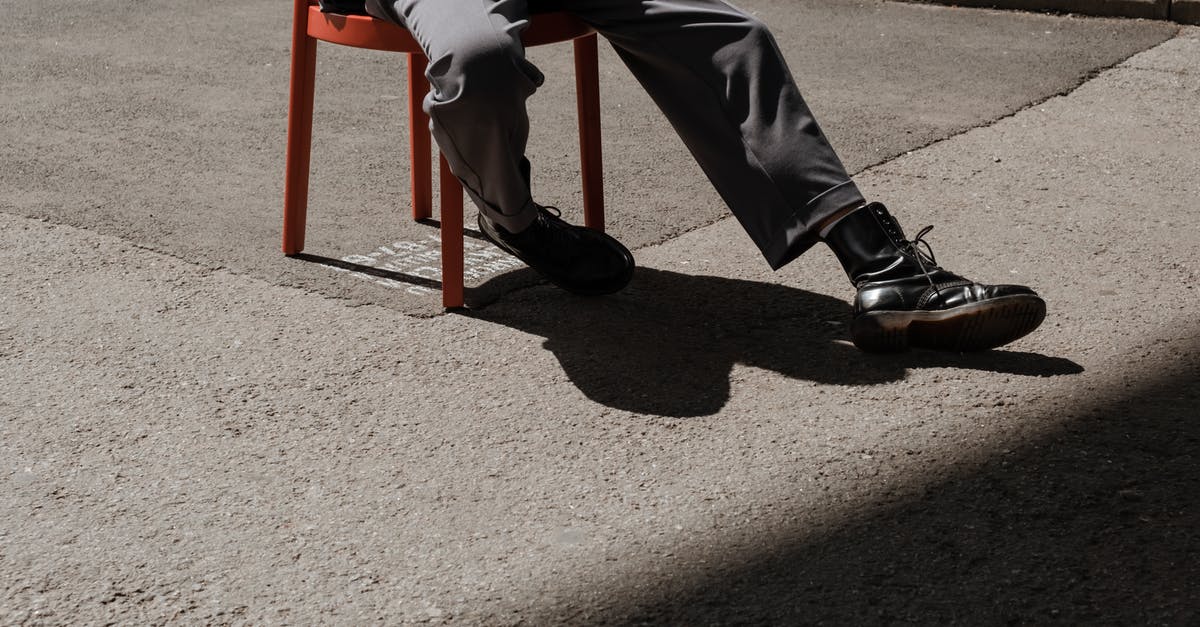 What to wear in Russia - Person in Black Pants and Black Shoes Sitting on Red Chair