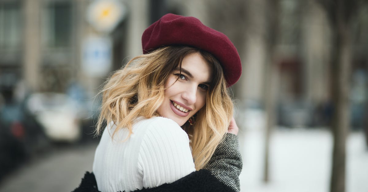What trousers/pants do women wear in Baltic cities in winter? - Selective Focus Photography of Smiling Woman Wearing Red Hat during Snowy Day