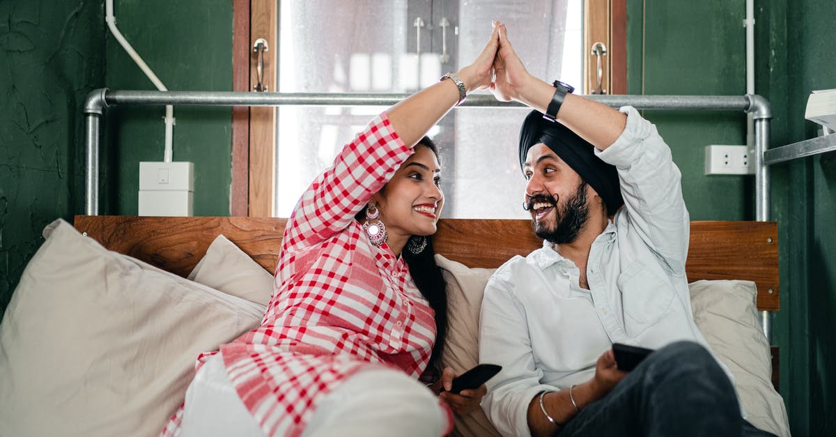 What was the meaning of this Indian gesture/greeting? - Young ethnic man and woman in casual outfit sitting in modern bedroom and enjoying weekend while doing high five on comfortable sofa