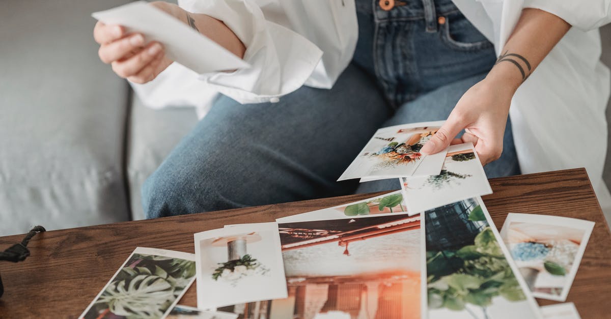 What’s different when airbnb'ing in a boat? - Crop unrecognizable tattooed female sitting on sofa at desk with assorted photos of flowers and town in house room