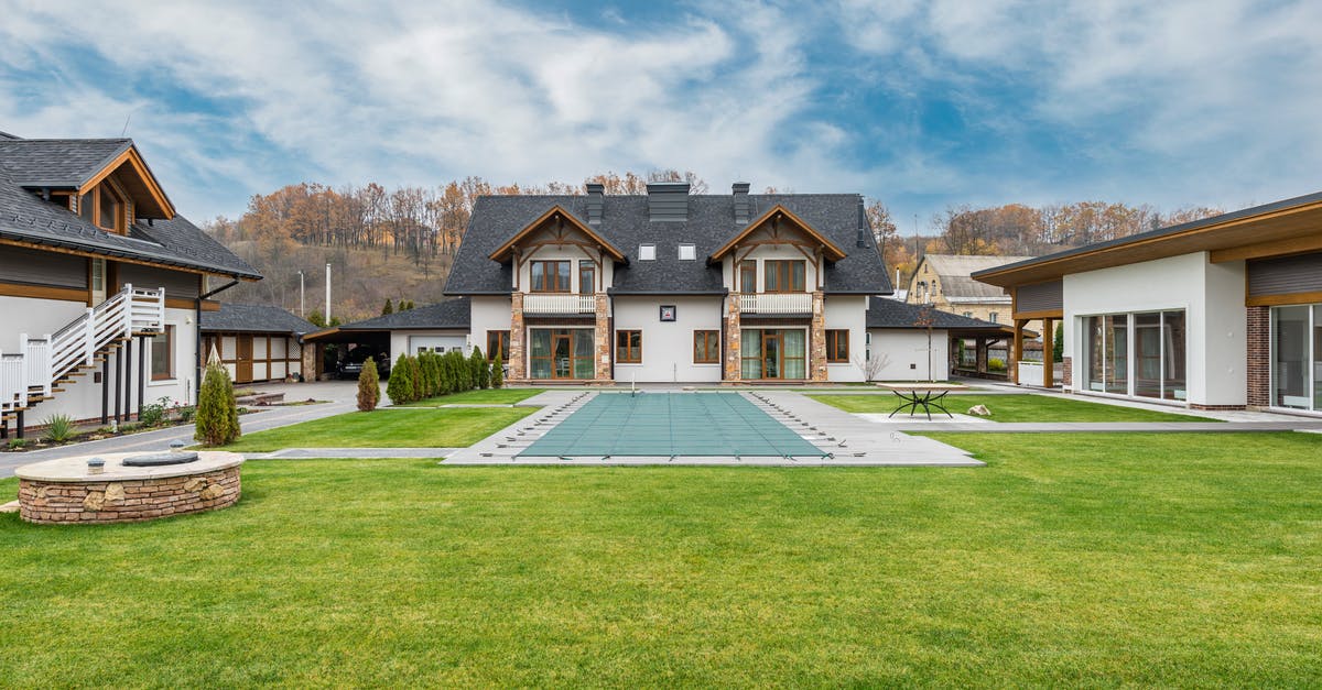 What/where is this large building with flags? - Exterior of contemporary residential cottage house with green lawn in yard under cloudy sky