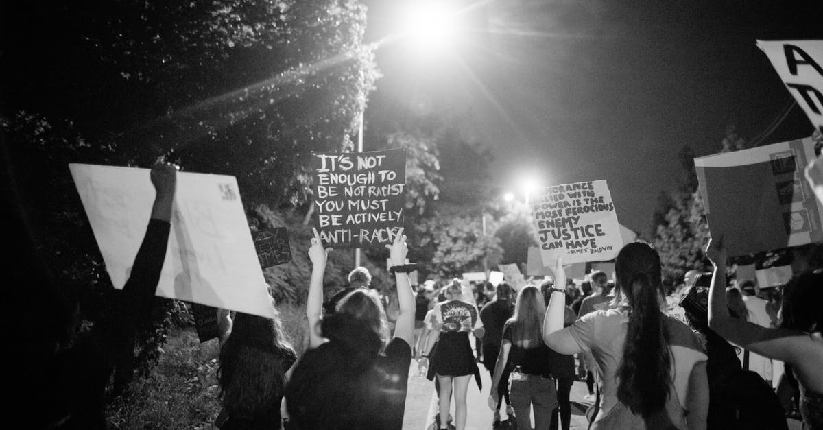 When do pedestrians have right of way in Australia? - Back view of black and white crowd of unrecognizable protesting people walking on street with banners during anti racism demonstration