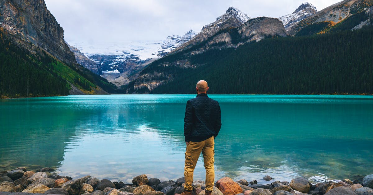When is the earliest time to visit Banff and Jasper for everything to be (re)opened? - Man in Blue Long Sleeve Shirt and Brown Pants Standing on Brown Wooden Dock