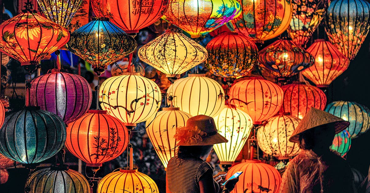 When is the peak travel time during Chinese New Year? - Two Person Standing Near Assorted-color Paper Lanterns