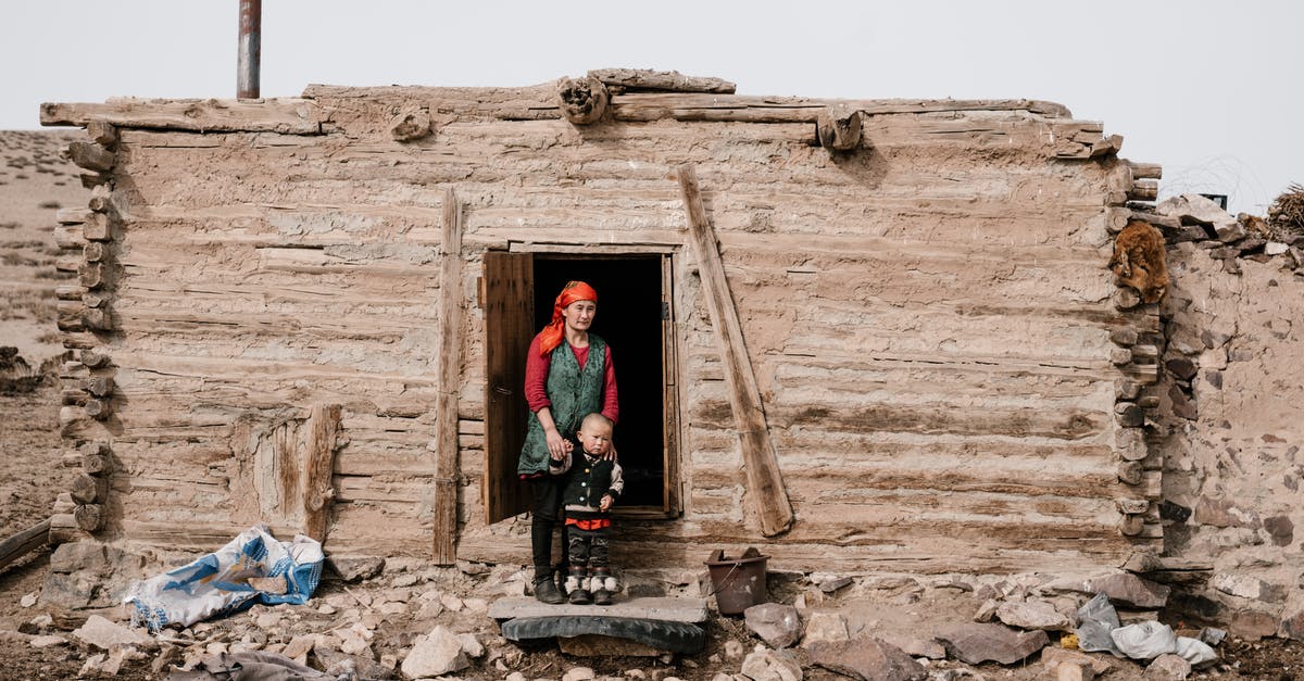 When transiting Beijing (PEK), citizens of which countries need visas? - Ethnic woman standing with little boy near entrance in ruined old building in countryside and looking away while holding hand of little child