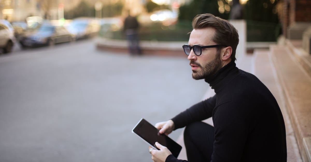 When visiting urban areas in Australia, do I need to be worried about deadly insects / animals? - Side view of trendy serious bearded male in glasses and black casual clothes with notebook looking away and thinking while sitting on exterior stairs at entrance of modern building in downtown