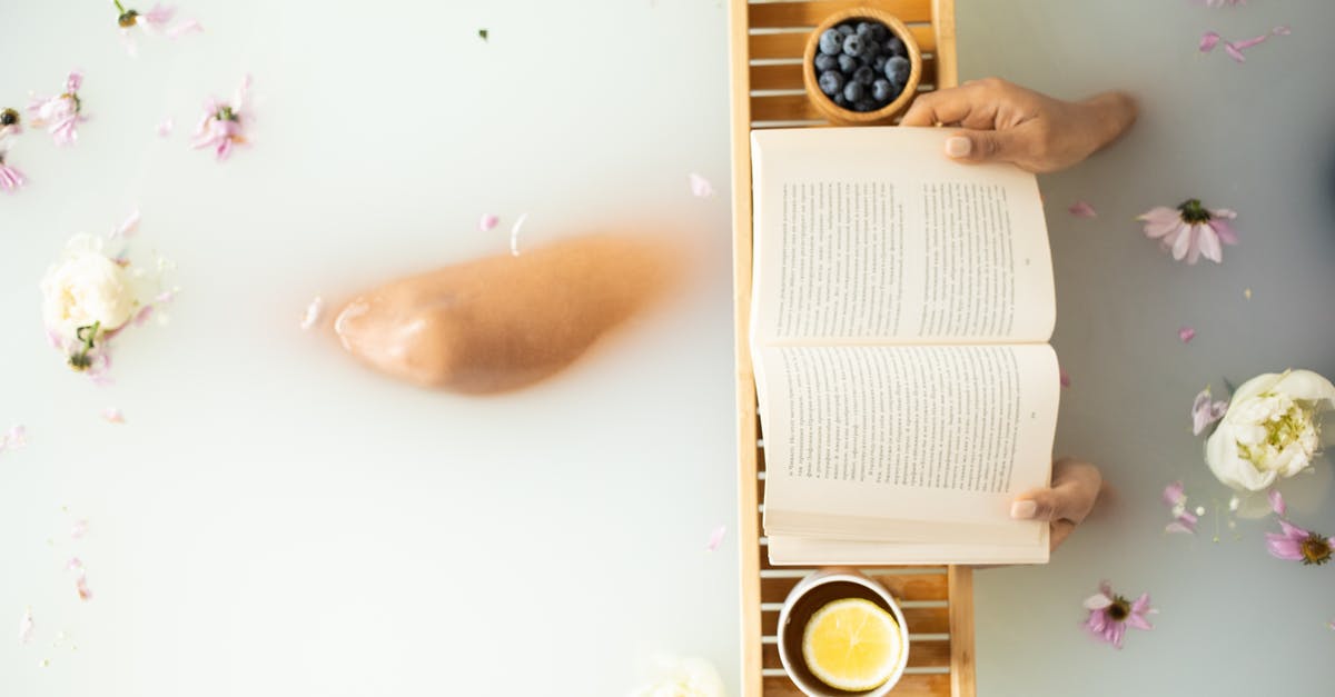 Where's the trailhead to Blueberry Hill? - Top view of crop unrecognizable lady in white water in bathtub with fresh colorful flower petals with wooden tray with cup of tea with lemon and blueberries while reading book