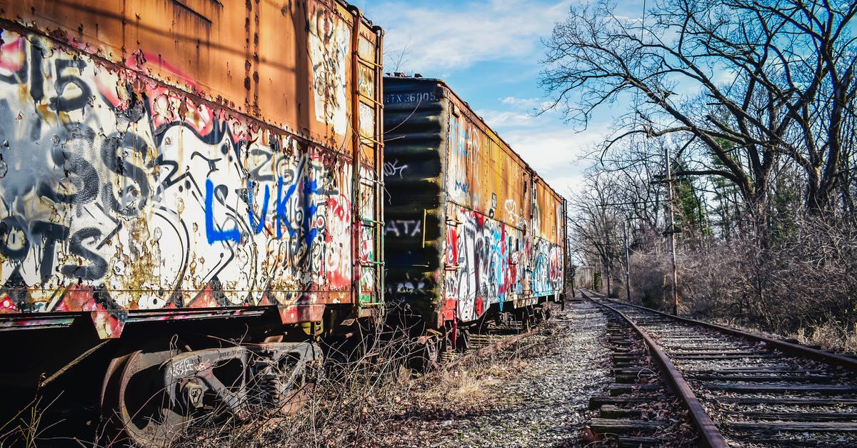 Where are open air railway carriages used in scheduled services? [closed] - Old railway carriages with graffiti on surface under cloudy sky