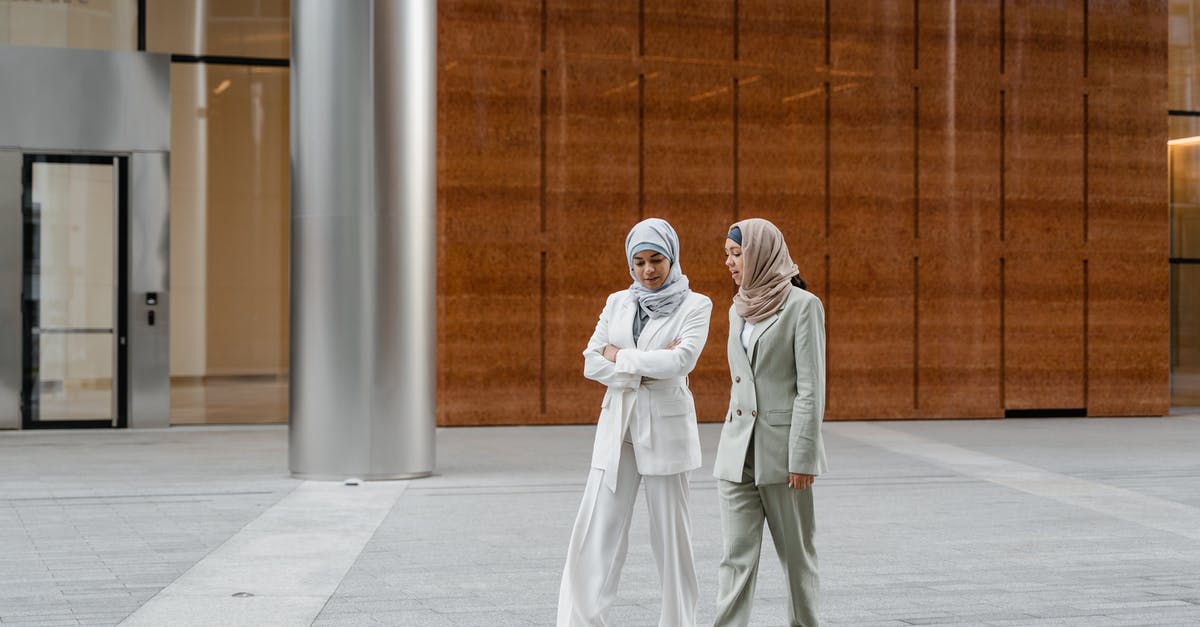 Where are these buildings? - 2 Women in White Hijab Standing on Gray Concrete Floor