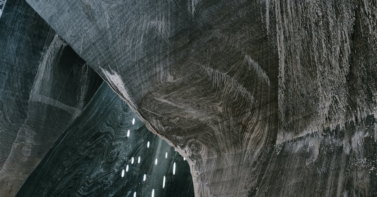 Where are these unusual rock formations rising from the water? - Low angle of abstract textured walls and hanging LED lamps in Salina Turda salt mine in Romania