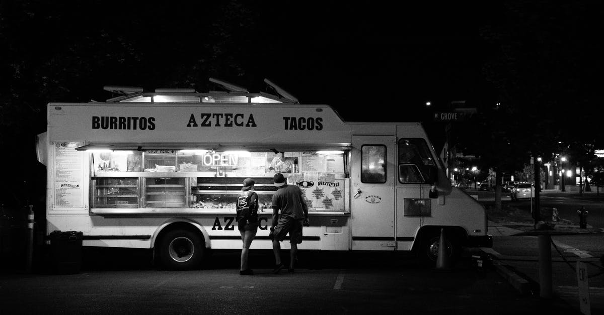 where can I buy bus tickets in Podgorica? - Grayscale Photograph of Two People Standing in Front of Food Truck