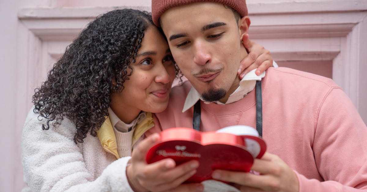 Where can I eat sushi with chocolate in it? - Joyful young ethnic couple embracing and eating yummy candies from heart shaped gift box during anniversary celebration