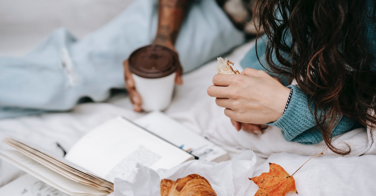 Where can I find and book plane tickets on date not on destination? - Unrecognizable multiracial couple with takeaway hot drink and croissant lying on white plaid with opened book during picnic in autumn day