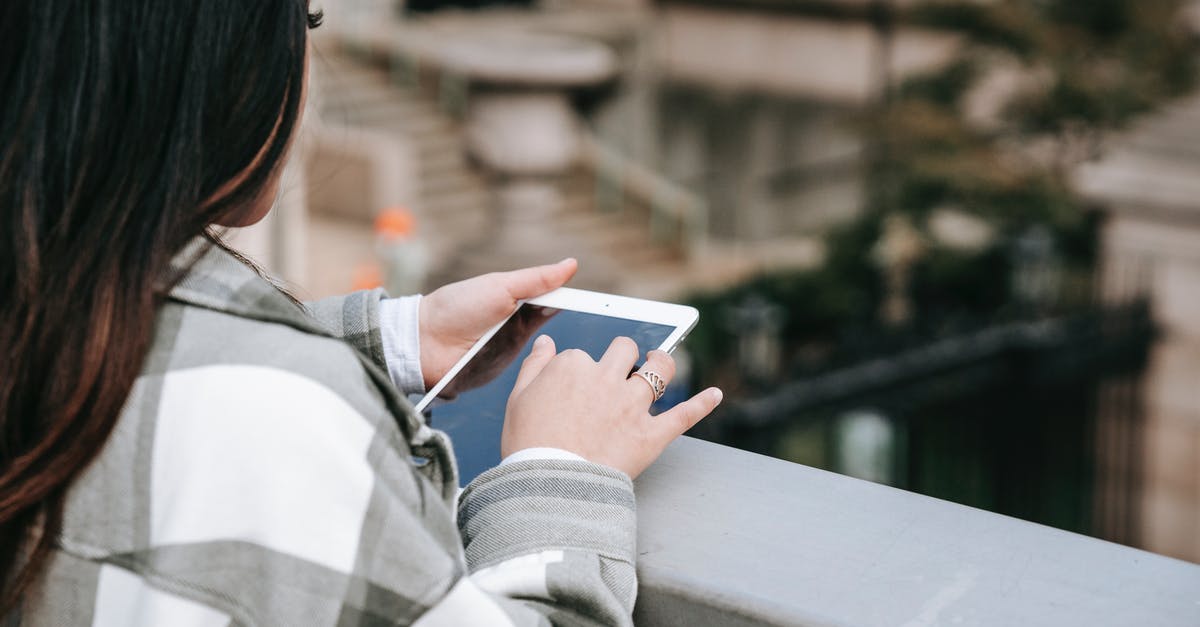 Where can I find the GWR web chat? - From above of crop unrecognizable young female in checkered shirt text messaging on tablet while standing near railing