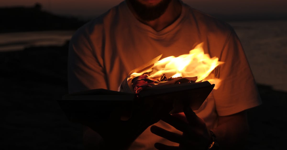 Where can I find tickets to Burning Man event? - A Man in White Shirt Holding a Burning Book