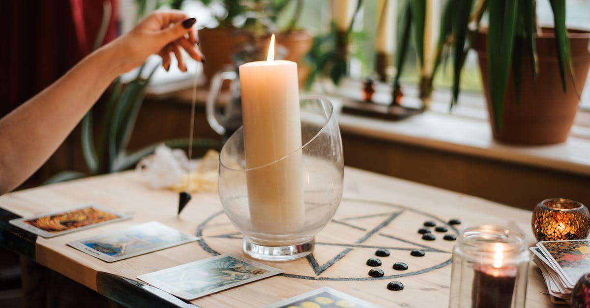 Where can I get an anonymous Rav Kav card issued? - Crop unrecognizable female fortune teller with amulet near tarot cards and shiny candles during prediction process at home